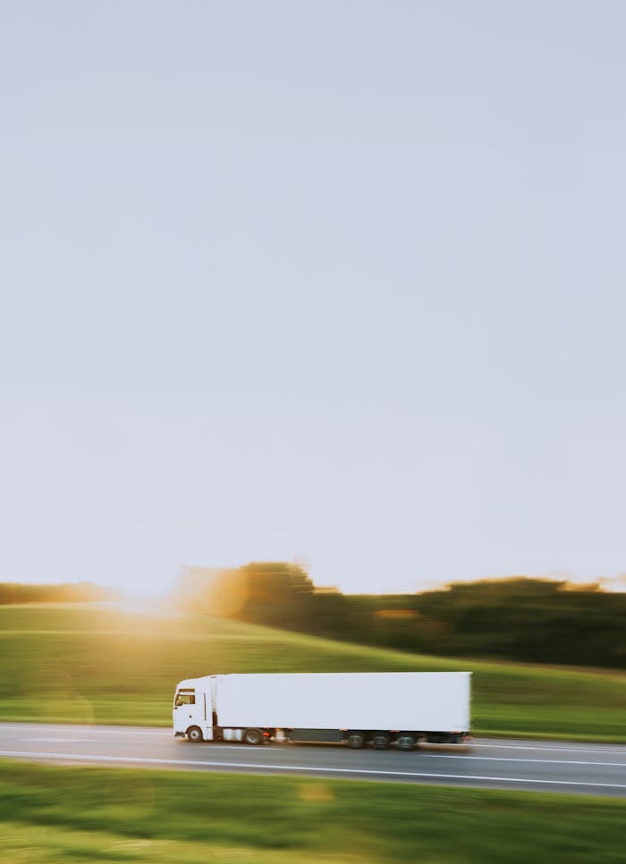 our-services-2 White cargo truck speeding through Vitebsk countryside at sunrise, symbolizing transportation and logistics.